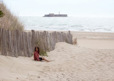 petite fille assise sur une plage vide